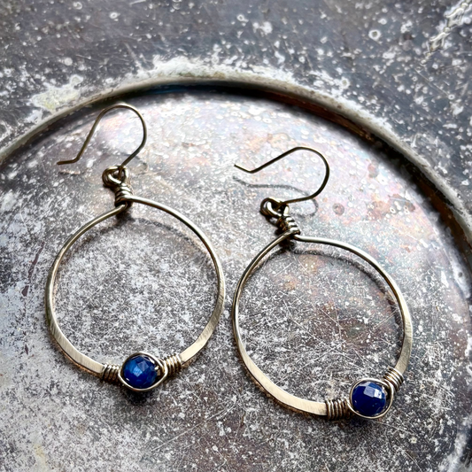 Pair of hoop earrings with blue stones on a textured surface
