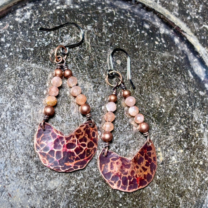 Pair of earrings with beaded design on a textured surface